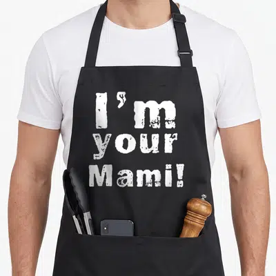 Mami mama mother's day aprons - White distressed text reading I'm your Mami stacked in three lines on dark background — shown on a black cotton canvas apron against a white background