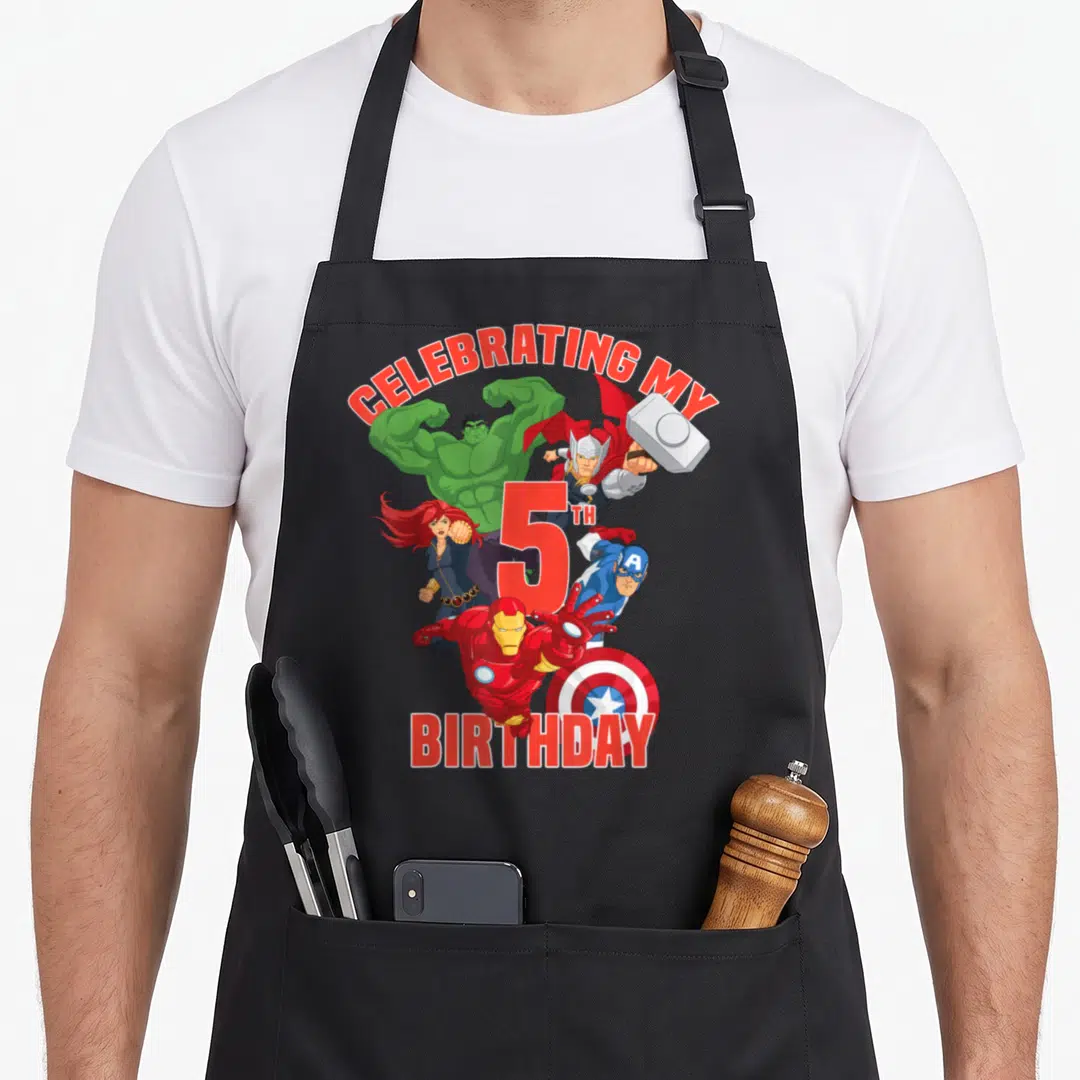 Celebrating birthday apron - Avengers cartoon characters surrounding red 5th birthday text on black apron — shown on a black cotton canvas apron against a white background