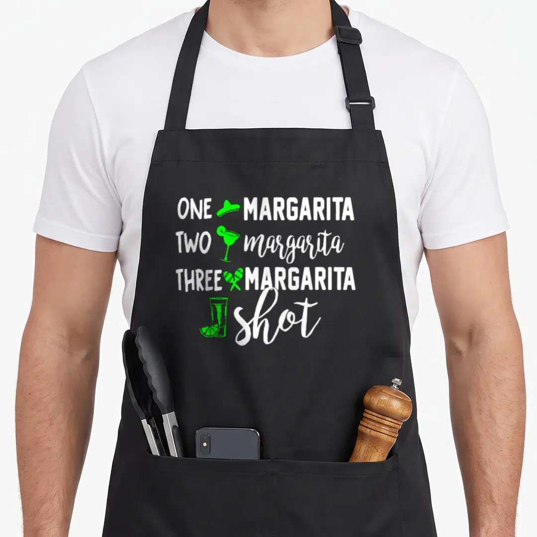 Three margarita apron - Stacked white text ONE MARGARITA TWO margarita THREE MARGARITA shot with green sombrero glass — shown on a black cotton canvas apron against a white background