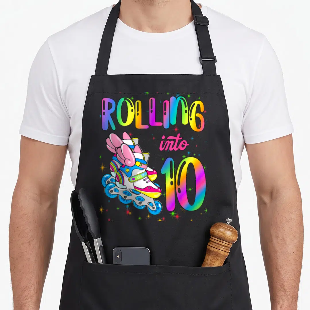 Cool rolling turning apron - Winged roller skate with rainbow text ROLLING into 10 and scattered stars — shown on a black cotton canvas apron against a white background