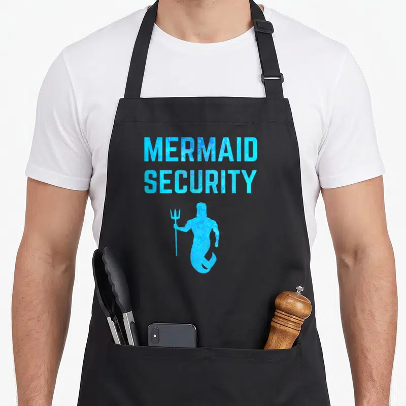 Majestic birthday apron - Blue Mermaid Security text above merman silhouette holding trident — shown on a black cotton canvas apron against a white background