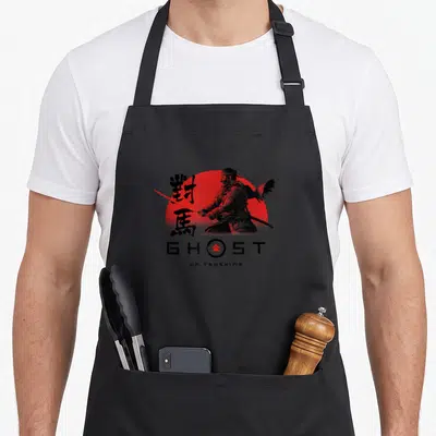 Tsushima ghost apron - Samurai silhouette against red sun with GHOST OF TSUSHIMA text and kanji — shown on a black cotton canvas apron against a white background