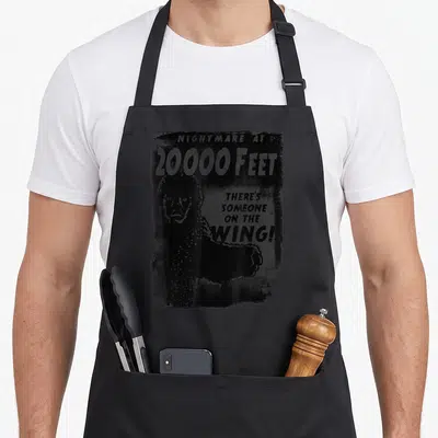 Wing twilight apron - Distressed black monster silhouette with Nightmare at 20000 Feet text and There's Someone — shown on a black cotton canvas apron against a white background