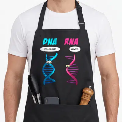 Dna biology apron - Blue DNA and pink RNA cartoon helices with speech bubbles reading still single always — shown on a black cotton canvas apron against a white background