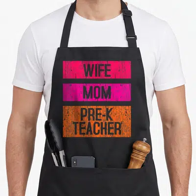 Pre best teacher apron - Stacked WIFE MOM PRE-K TEACHER text in distressed pink and orange rectangles — shown on a black cotton canvas apron against a white background