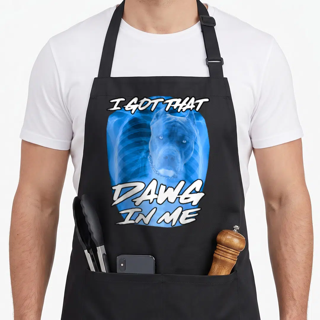 Dawg meme apron - Blue X-ray ribcage with pitbull head and white text I GOT THAT DAWG IN ME — shown on a black cotton canvas apron against a white background