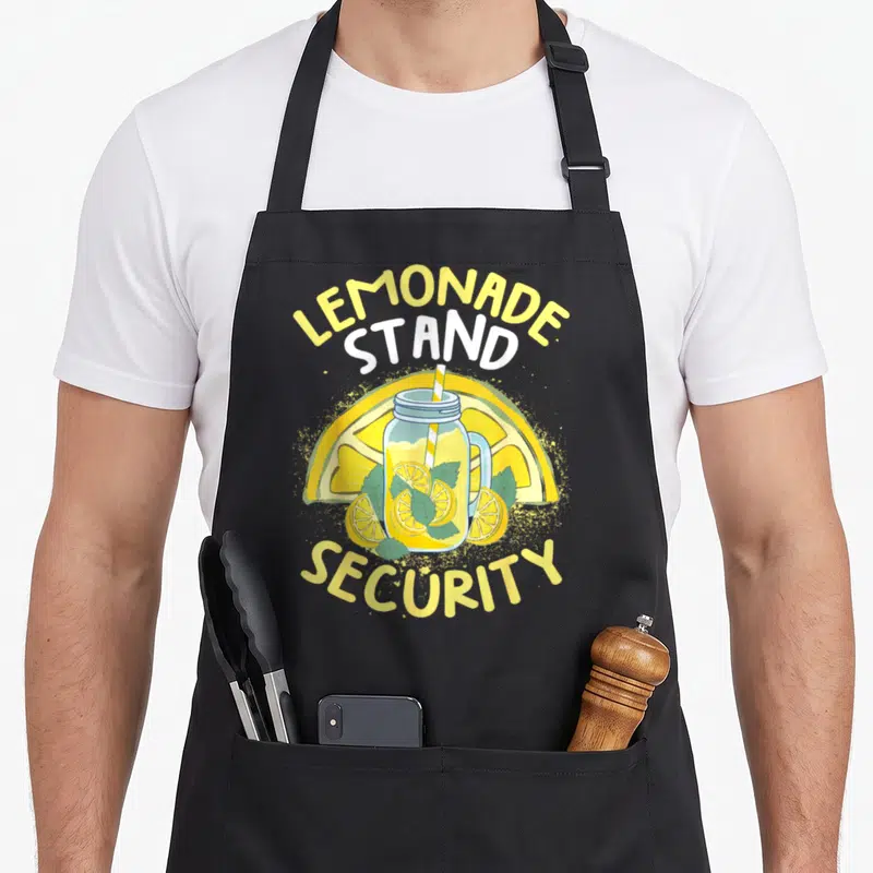 Summer stand lemonade apron - Lemonade Stand Security text with mason jar, lemon slices, and mint in cartoon style — shown on a black cotton canvas apron against a white background