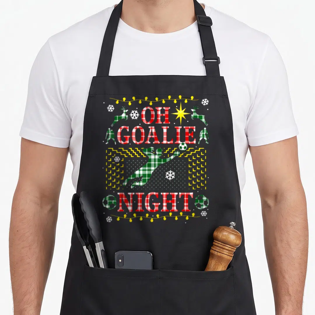 Soccer ugly sweater apron - OH GOALIE NIGHT text with plaid goalkeeper jumping and reindeer border — shown on a black cotton canvas apron against a white background
