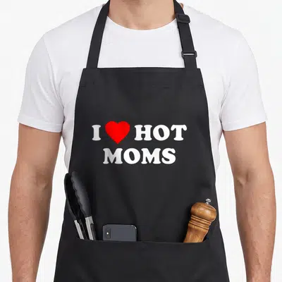 Cute love hot apron - White I and HOT letters with red heart between them and MOMS centered below in bold font — shown on a black cotton canvas apron against a white background