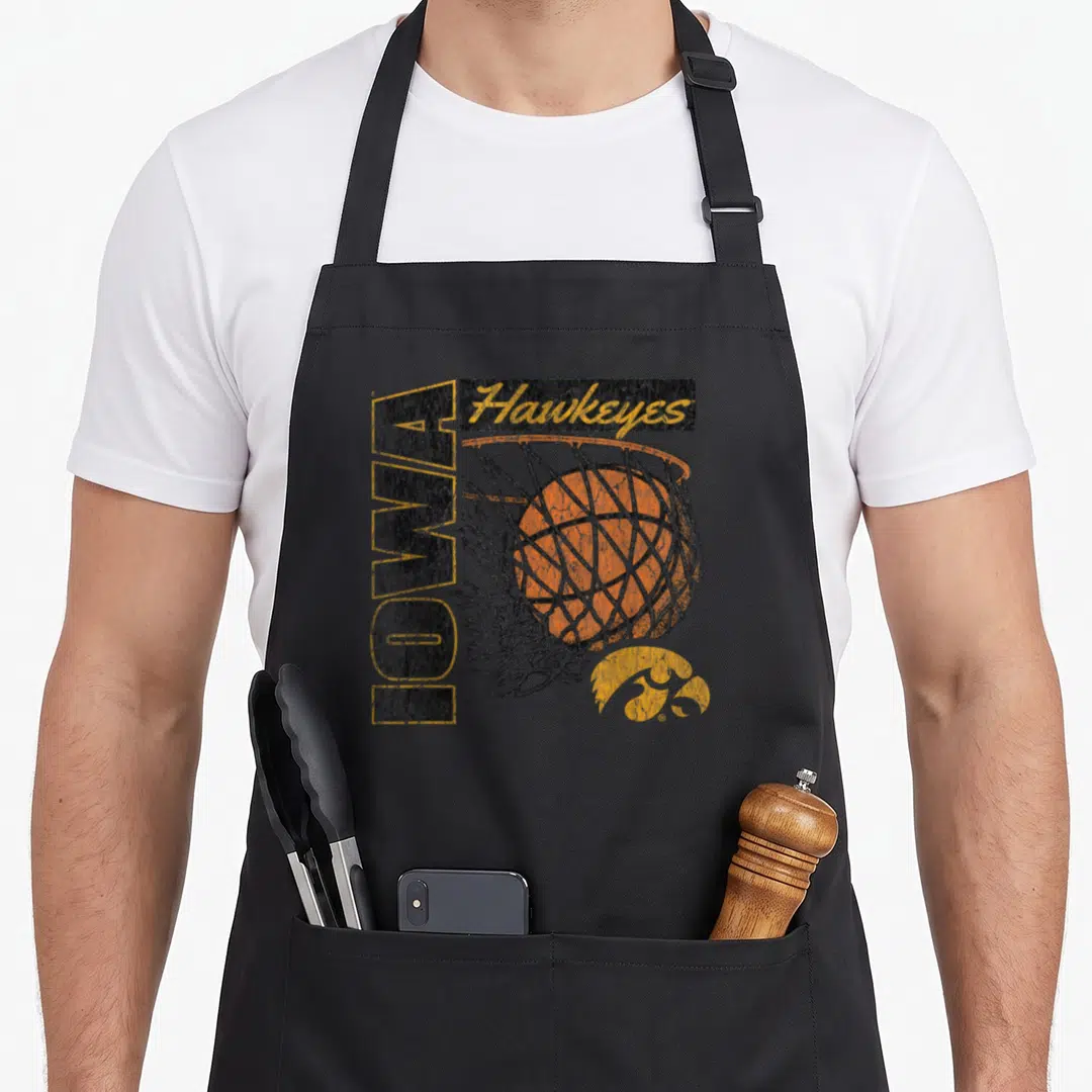 Iowa 90s apron - Vertical Iowa text, Hawkeyes script, orange basketball in grey net, yellow bird logo, distressed style — shown on a black cotton canvas apron against a white background