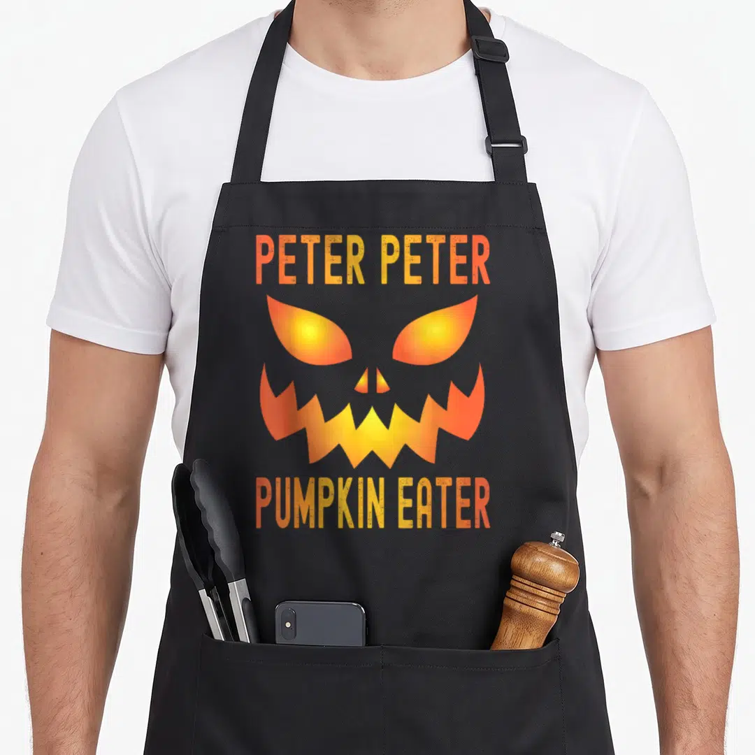 Costume peter halloween apron - PETER PETER PUMPKIN EATER text surrounding a glowing orange and yellow minimalist — shown on a black cotton canvas apron against a white background