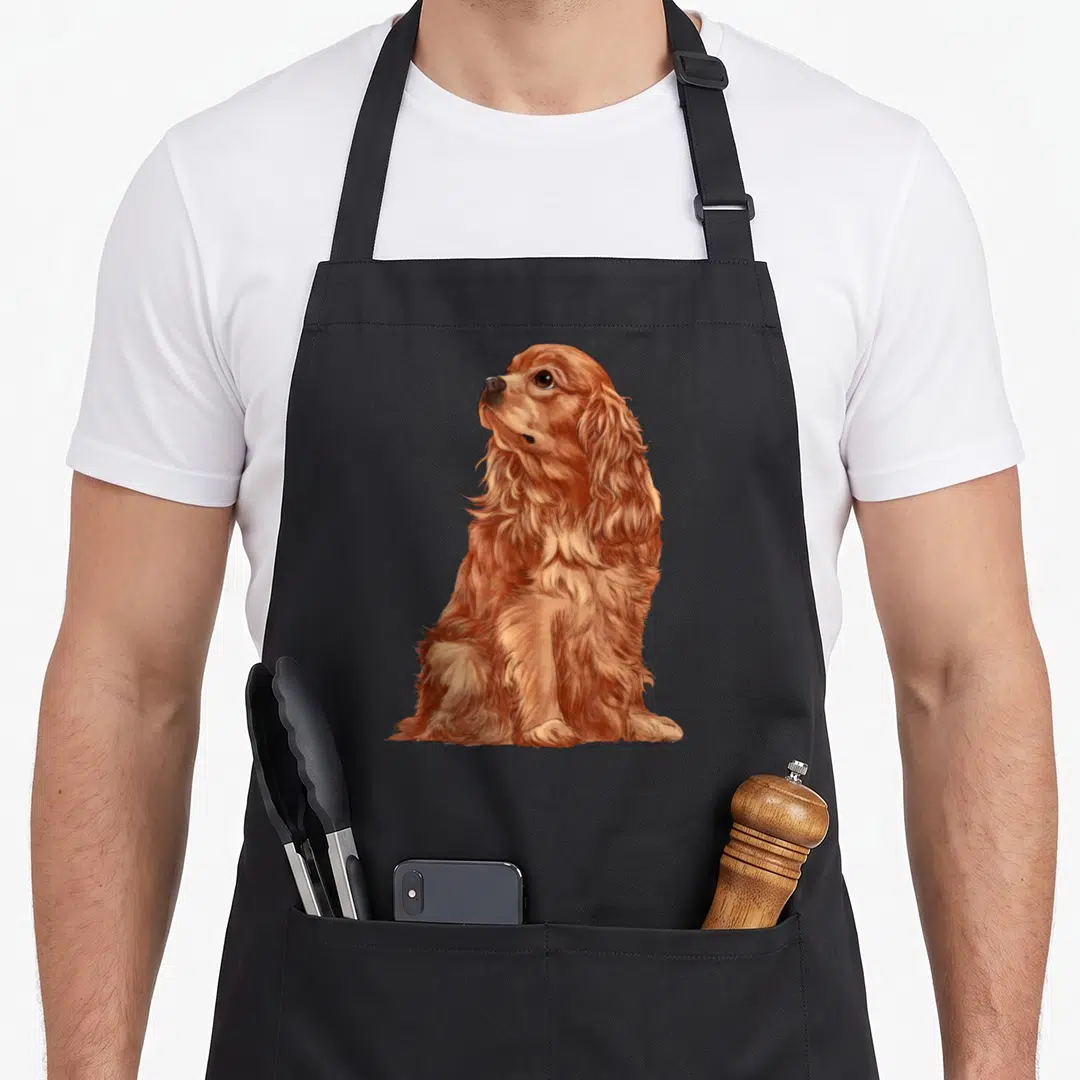 Cavalier charle spaniel dog king apron - Realistic brown and tan dog sitting and looking upwards to the left — shown on a black cotton canvas apron against a white background
