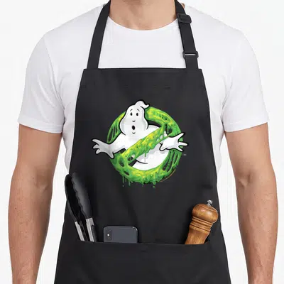 Slime ghost apron - Cartoon white ghost inside a ring of dripping green slime with black outlines — shown on a black cotton canvas apron against a white background
