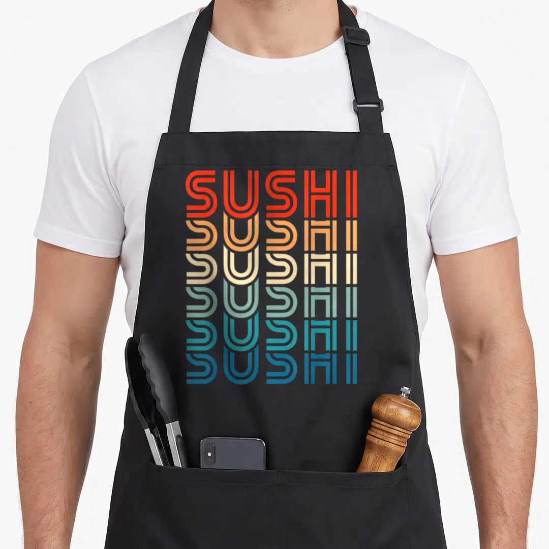Carb sushi apron - Stacked SUSHI text in red, orange, beige, green, teal, and blue retro font — shown on a black cotton canvas apron against a white background