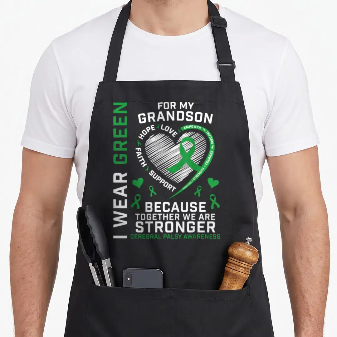 Cerebral grandma apron - I WEAR GREEN text, white sketched heart, green ribbon, and Cerebral Palsy Awareness words — shown on a black cotton canvas apron against a white background