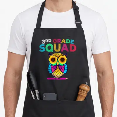 Owl teacher apron - 3rd Grade Squad text above a colorful cartoon owl with sunflower eyes perched on a pink pencil — shown on a black cotton canvas apron against a white background