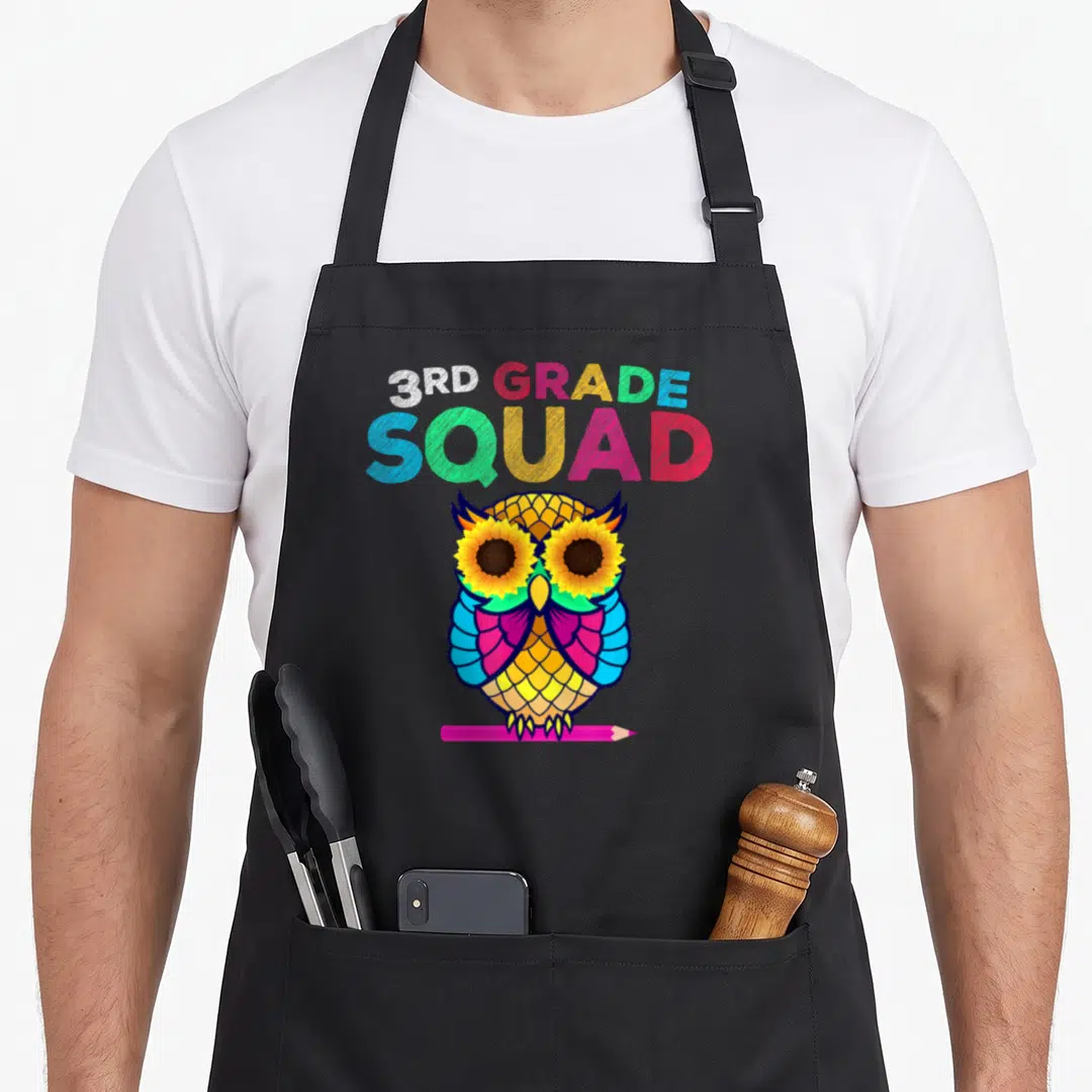 Owl teacher apron - 3rd Grade Squad text above a colorful cartoon owl with sunflower eyes perched on a pink pencil — shown on a black cotton canvas apron against a white background