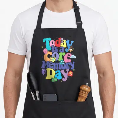 Today memory apron - Stacked colorful bubble text reading Today is a core Memory Day surrounded by emotion characters — shown on a black cotton canvas apron against a white background