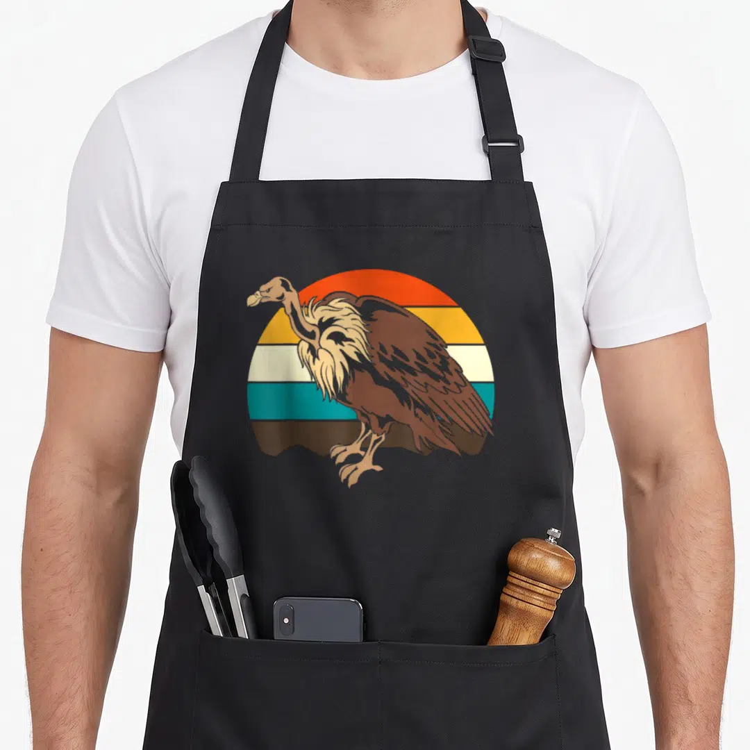 Scavenger bird apron - Brown vulture standing before orange teal and tan retro striped semi-circle background — shown on a black cotton canvas apron against a white background