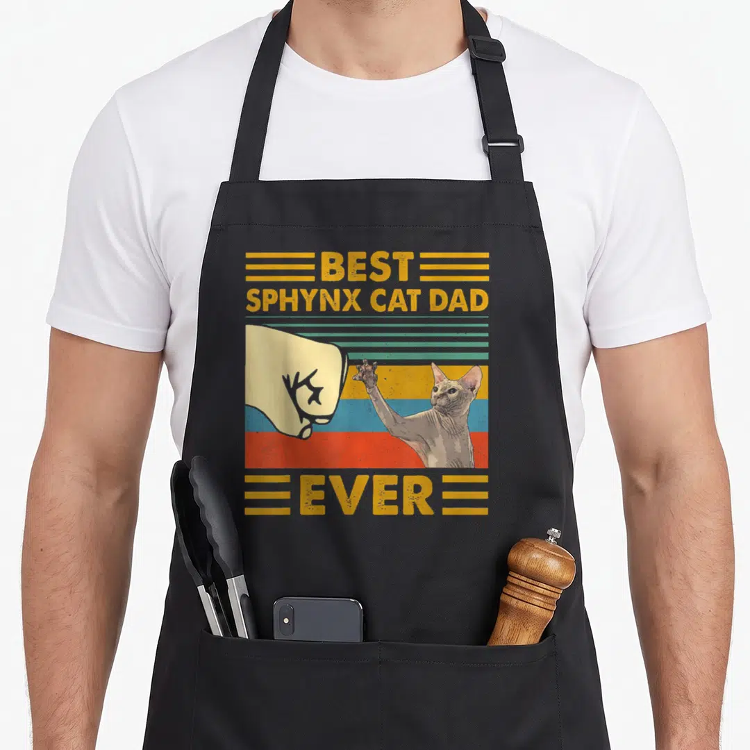 Sphynx sunset cat apron - Retro fist bump between human hand and sphynx cat with best sphynx cat dad ever text — shown on a black cotton canvas apron against a white background