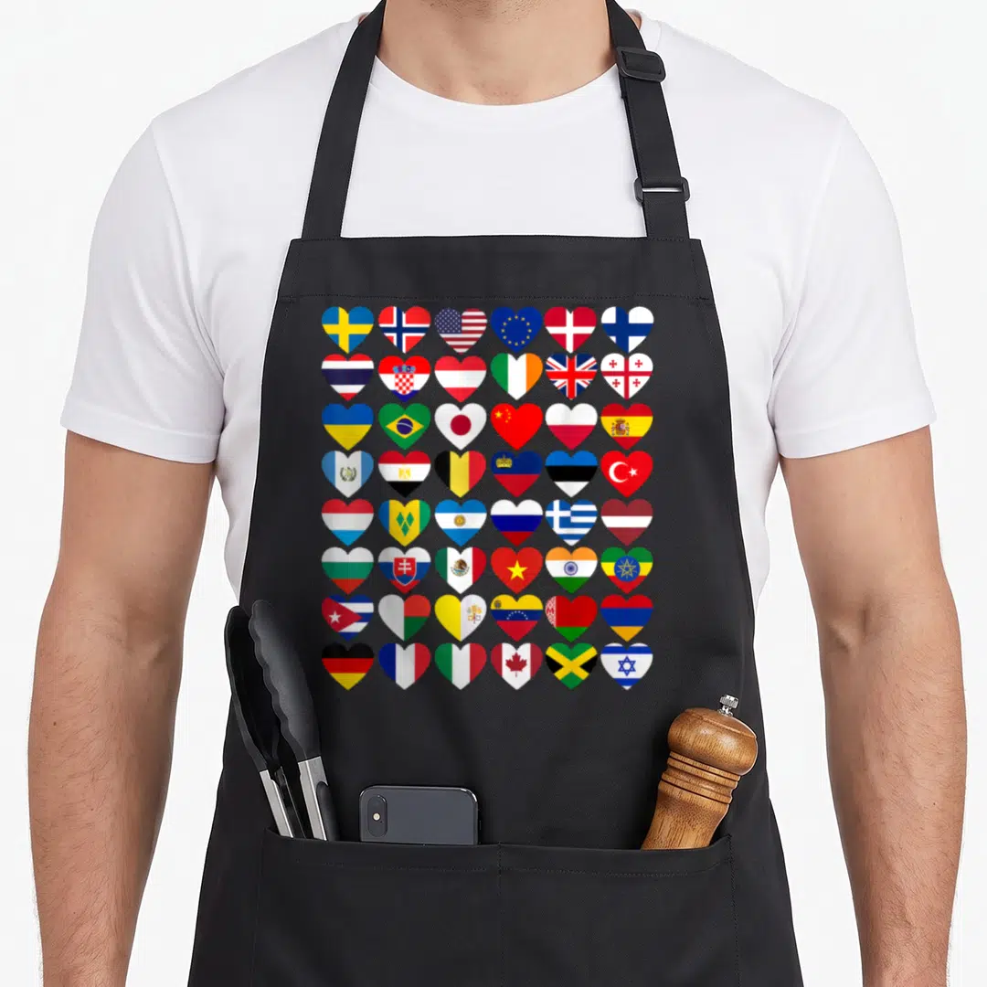 Flag country apron - 48 heart-shaped national flags in red blue yellow green white grid — shown on a black cotton canvas apron against a white background