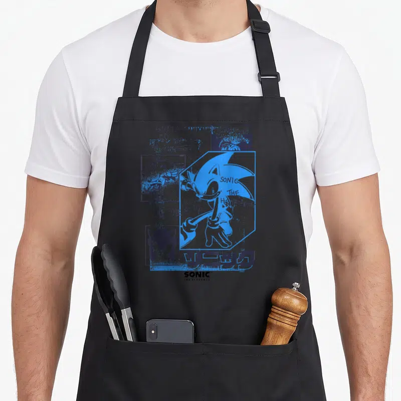 Fast crazy hedgehog apron - Blue Sonic collage with GOTTA GO FAST text and Japanese characters on grey background — shown on a black cotton canvas apron against a white background
