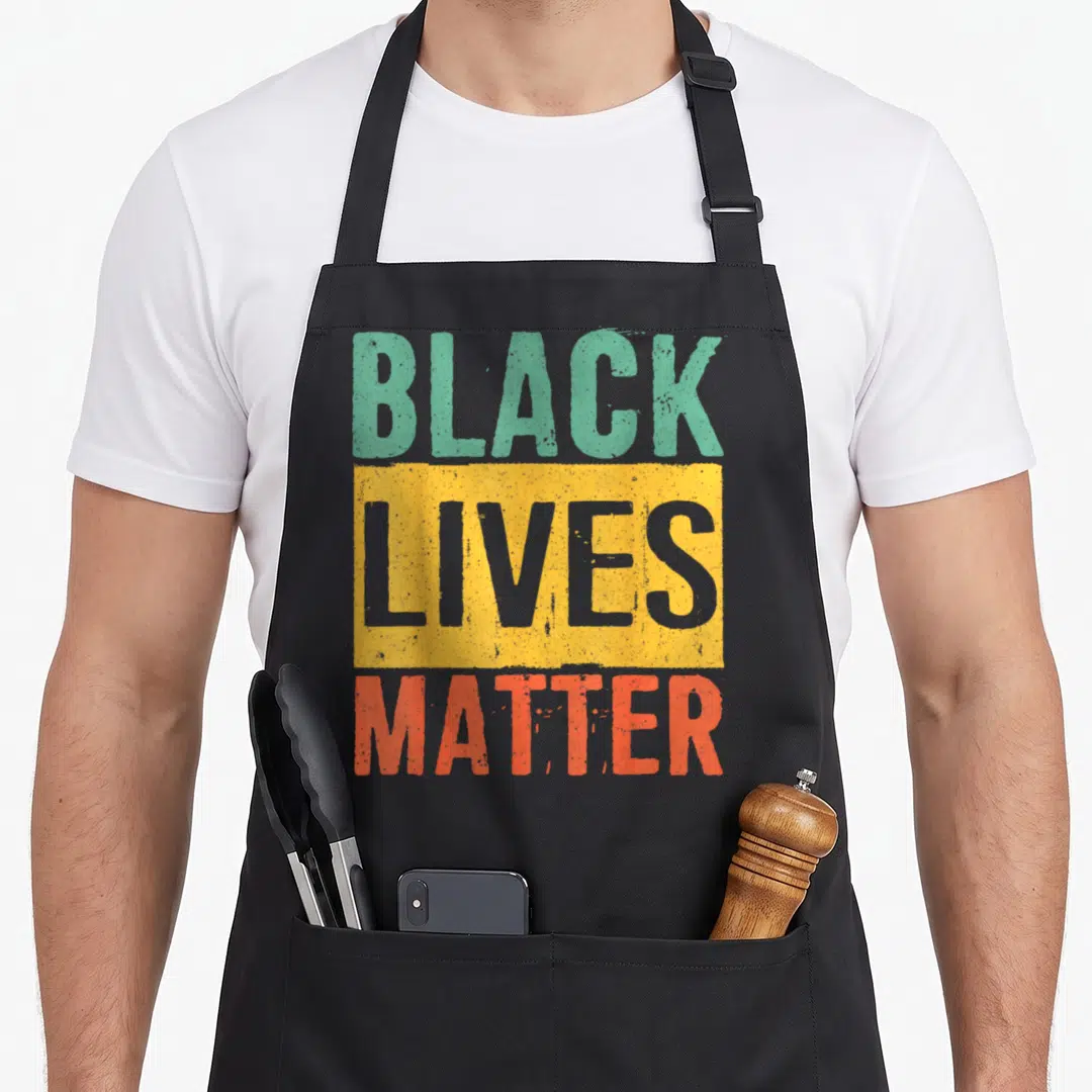 Matter african american aprons - Stacked BLACK LIVES MATTER text in green yellow red grey distressed font — shown on a black cotton canvas apron against a white background