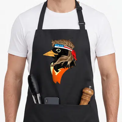 Oriole trendy apron - Cartoon bird head with mullet, mustache, and patriotic bandana in black and orange — shown on a black cotton canvas apron against a white background