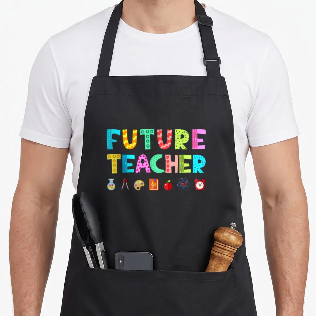 Career teacher apron - Stacked FUTURE TEACHER text with colorful school icons like apple and beaker — shown on a black cotton canvas apron against a white background