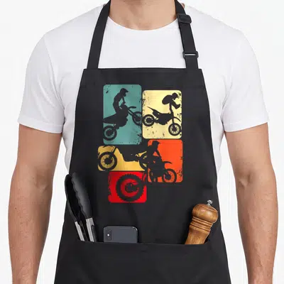 Rider motocross enduro bike apron - Four teal yellow orange and red rounded squares with grey dirt bike rider — shown on a black cotton canvas apron against a white background
