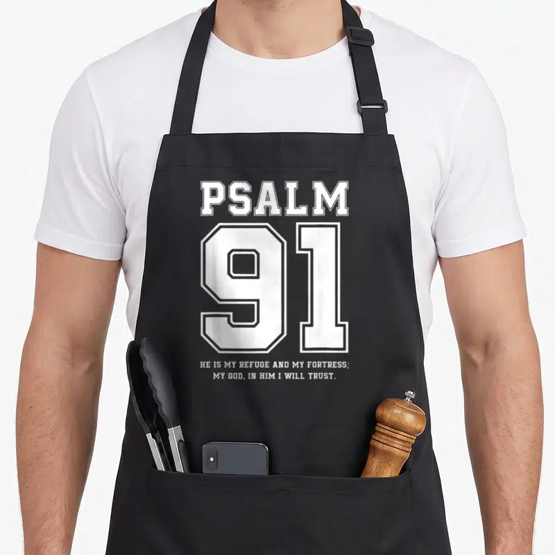 Refuge christian apron - White PSALM 91 typography with He Is My Refuge verse stacked vertically — shown on a black cotton canvas apron against a white background