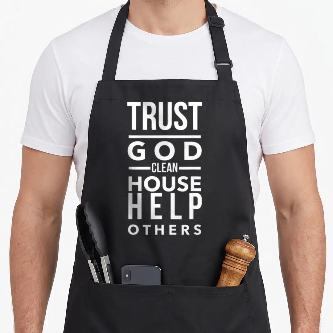 Trust help the house apron - White stacked text reading TRUST GOD CLEAN HOUSE HELP OTHERS with horizontal separators — shown on a black cotton canvas apron against a white background