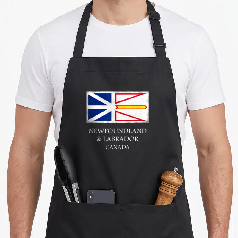 Canada labrador apron - Distressed Newfoundland and Labrador flag with stacked white text on black fabric — shown on a black cotton canvas apron against a white background