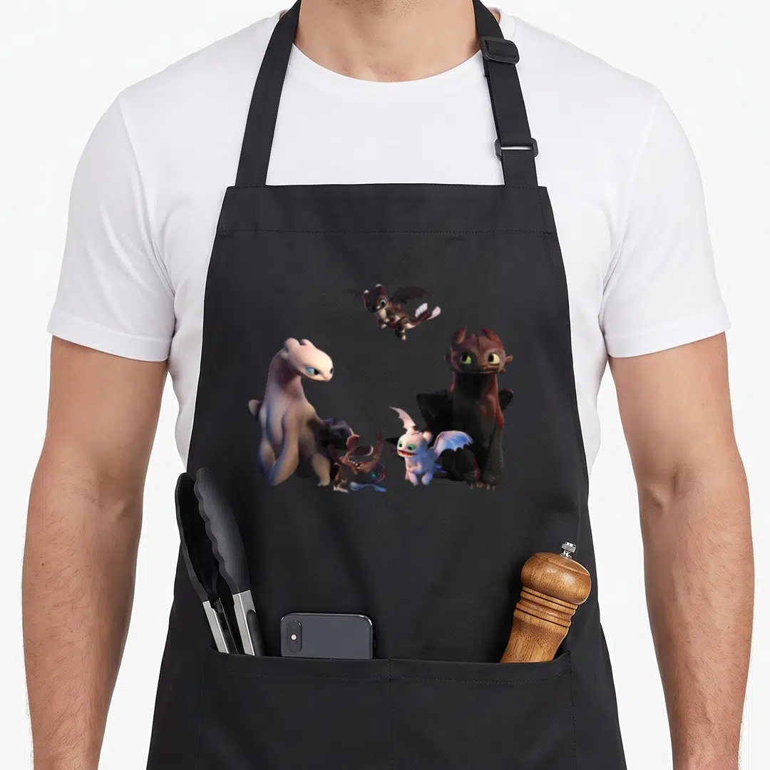 Train family aprons - Four cartoon dragons in black, white, and grey clustered together — shown on a black cotton canvas apron against a white background