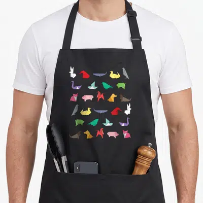 Animal paper apron - Grid of thirty colorful origami animals including rabbits, swans, whales, birds, pigs, dogs — shown on a black cotton canvas apron against a white background