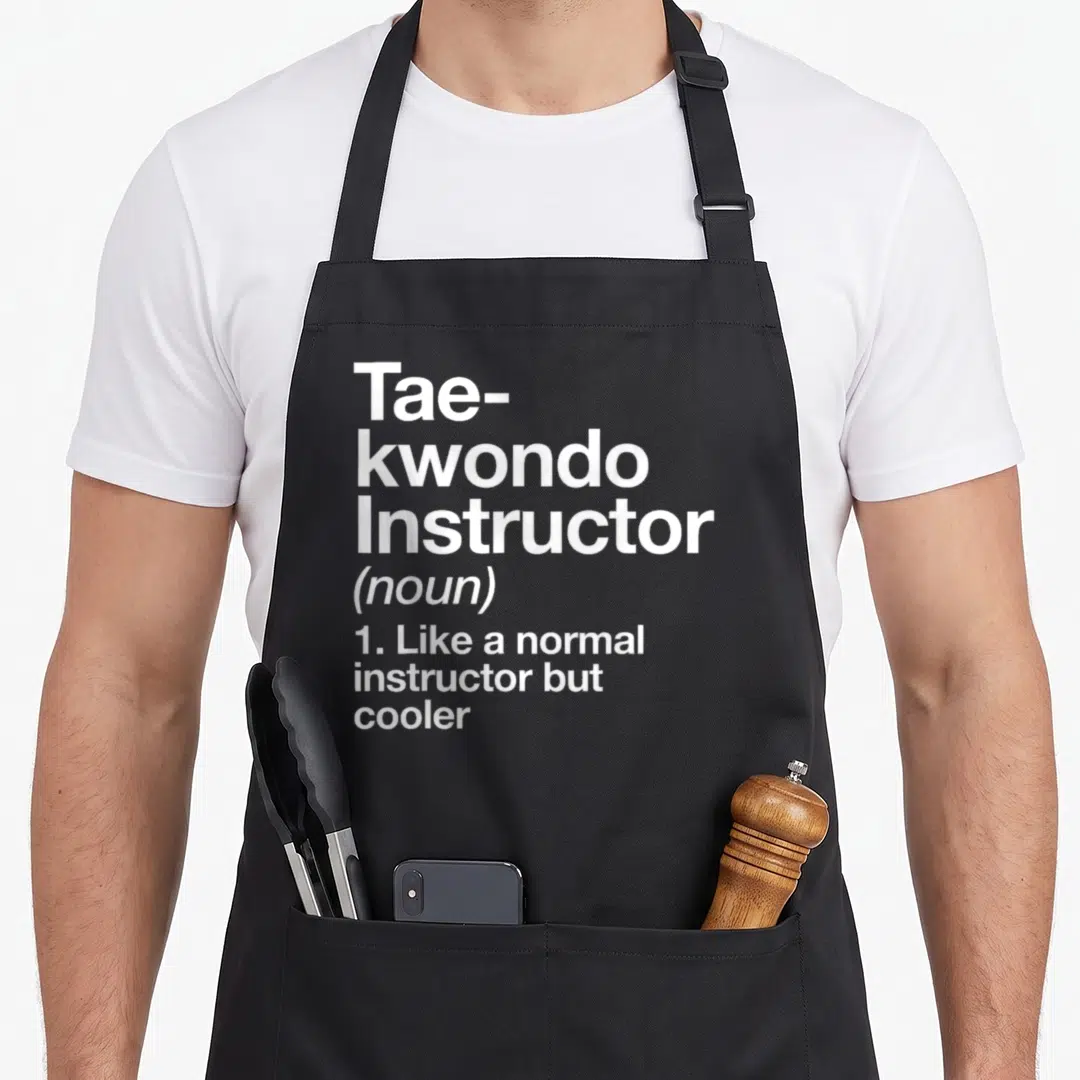 Instructor martial apron - White stacked text reading Tae-kwondo Instructor noun like normal but cooler — shown on a black cotton canvas apron against a white background