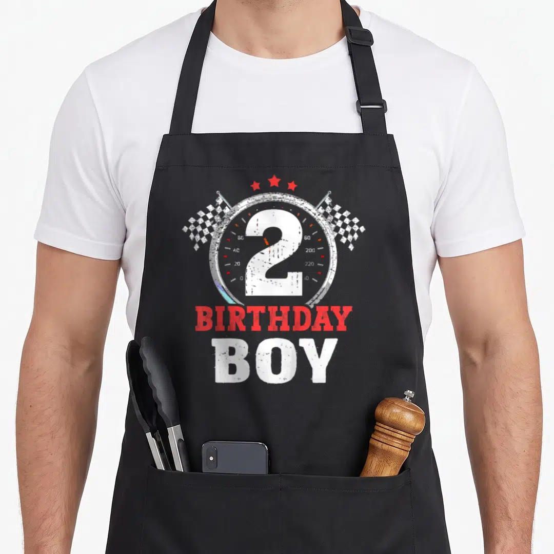 Racing 2nd apron - Distressed speedometer with number 2, checkered flags, and BIRTHDAY BOY text — shown on a black cotton canvas apron against a white background