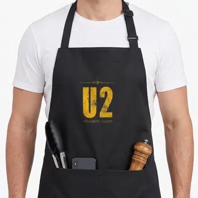 Aeroplane dragon apron - Yellow U2 text and small plane silhouette above Dragon Lady words on black apron — shown on a black cotton canvas apron against a white background