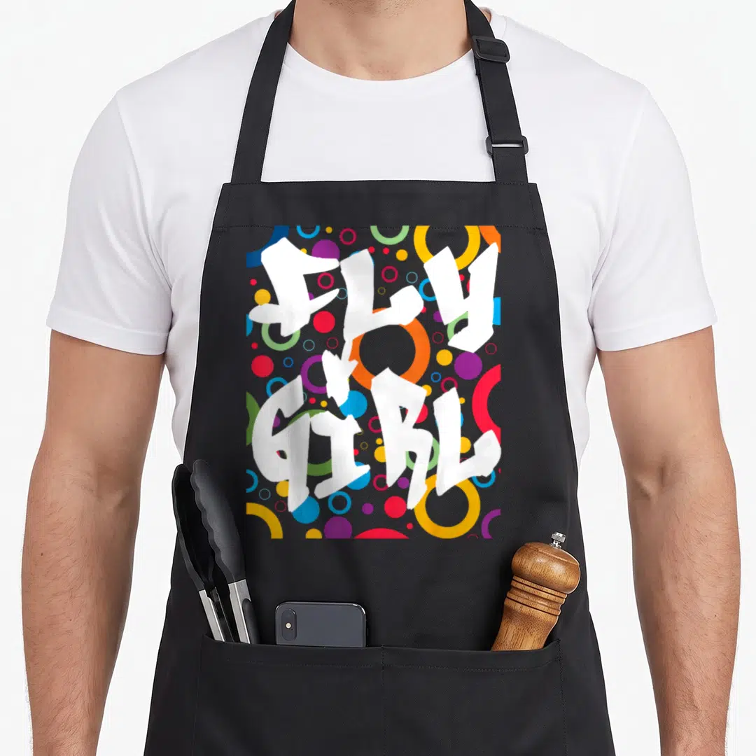 Fly hip apron - Stacked white FLY GIRL text over blue yellow red purple and multicolored circles — shown on a black cotton canvas apron against a white background