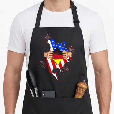 Germany blood american flag apron - USA map with US flag torn open by hands to reveal German flag stripes — shown on a black cotton canvas apron against a white background