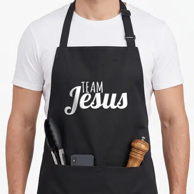 Jesus christianity cross apron - White stacked TEAM Jesus text on black apron background — shown on a black cotton canvas apron against a white background