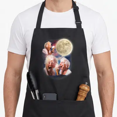 Moon granny apron - Three elderly women eating ice cream under a large moon with purple and yellow clouds — shown on a black cotton canvas apron against a white background