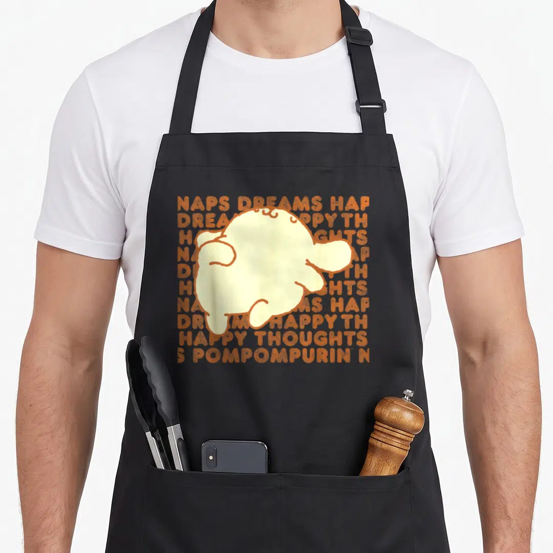 Thought pompompurin apron - Pale yellow Pompompurin silhouette overlapping orange text blocks reading NAPS DREAMS HAP — shown on a black cotton canvas apron against a white background