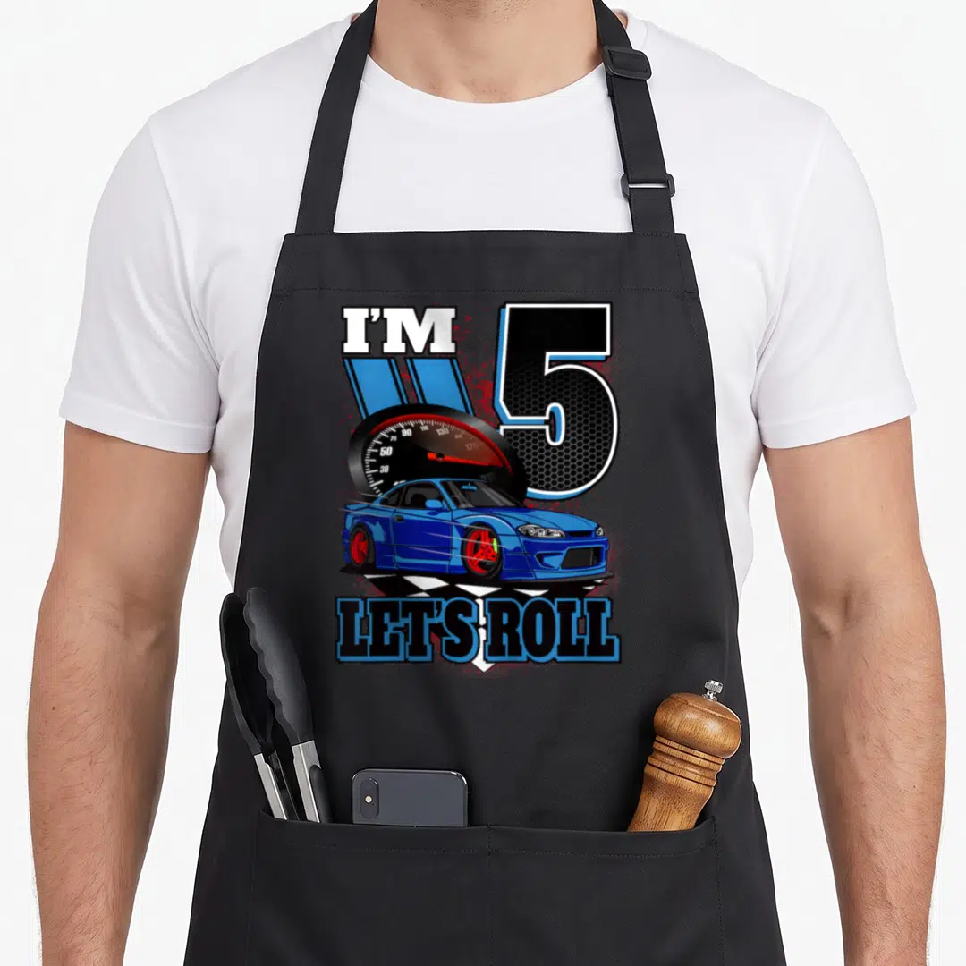 Birthday 5th car apron - I'M 5 LET'S ROLL text with blue car, speedometer, checkered flag, red splatter accents — shown on a black cotton canvas apron against a white background