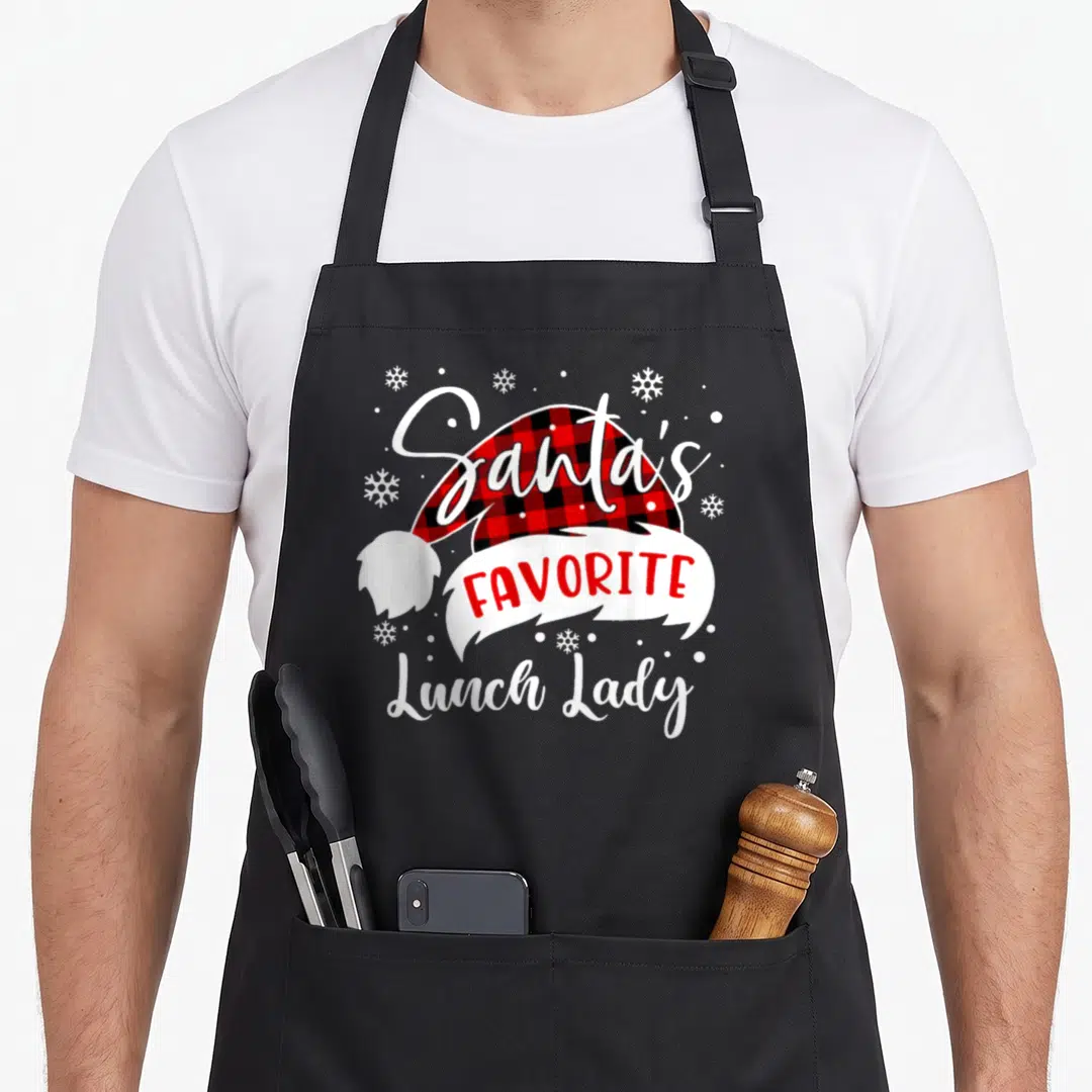 Santas lunch lady apron - Santa hat with red black plaid and Santa's Favorite Lunch Lady text surrounded by snowflakes — shown on a black cotton canvas apron against a white background
