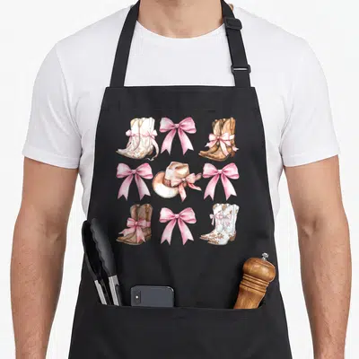 Bow cowgirl aprons - Grid of pink bows, cowboy boots, and hat in pink white brown beige realistic art — shown on a black cotton canvas apron against a white background