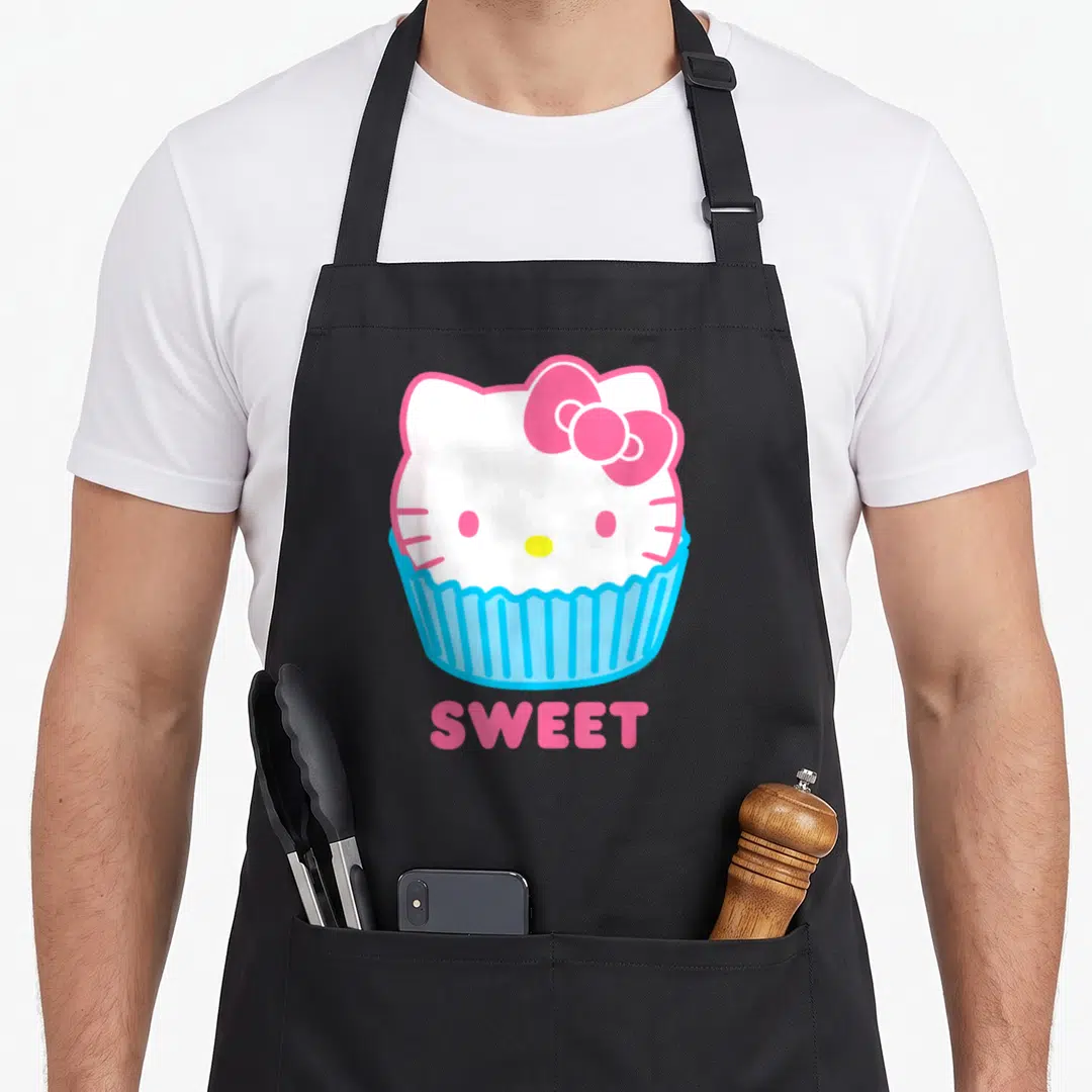 Sweet cupcake apron - Hello Kitty head in blue cupcake liner with pink bow and SWEET text — shown on a black cotton canvas apron against a white background