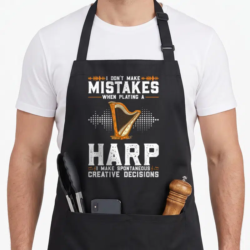 Funny harp apron - Orange harp on white dots with I don't make mistakes text on grey — shown on a black cotton canvas apron against a white background