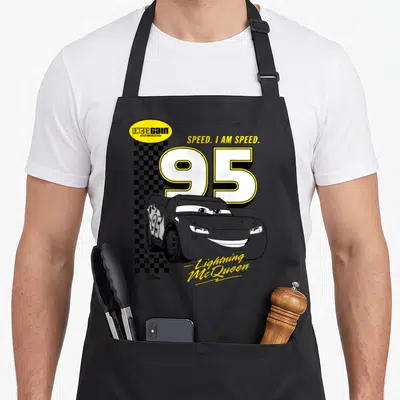 Speed car apron - Lightning McQueen 95 with octane GAIN logo and checkered flag pattern — shown on a black cotton canvas apron against a white background