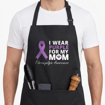 Fibromyalgia i love production apron - Purple awareness ribbon next to stacked white text reading I Wear Purple For My — shown on a black cotton canvas apron against a white background